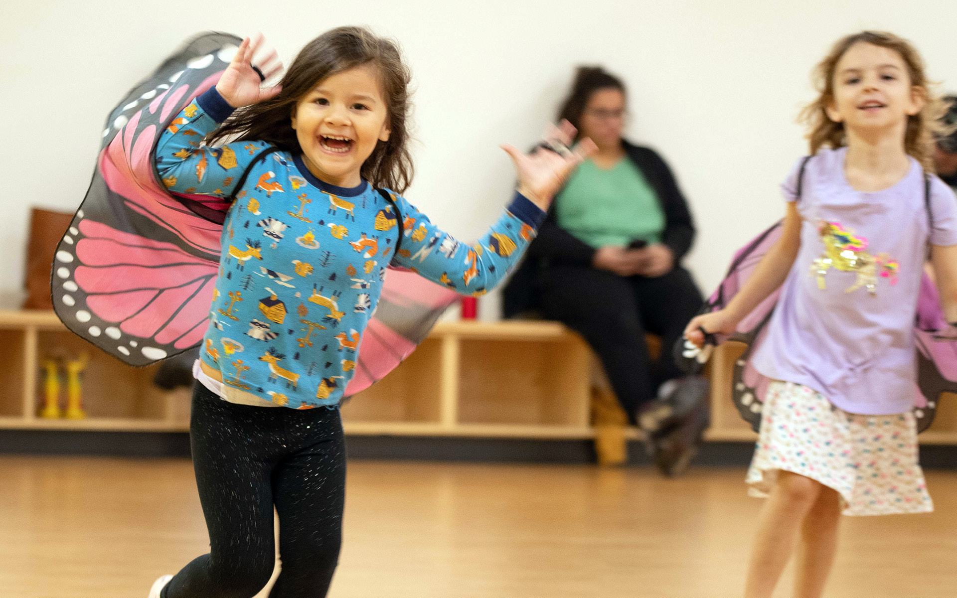 Young girl wearing butterfly wings gleefully participates in GBYMCA youth dance class